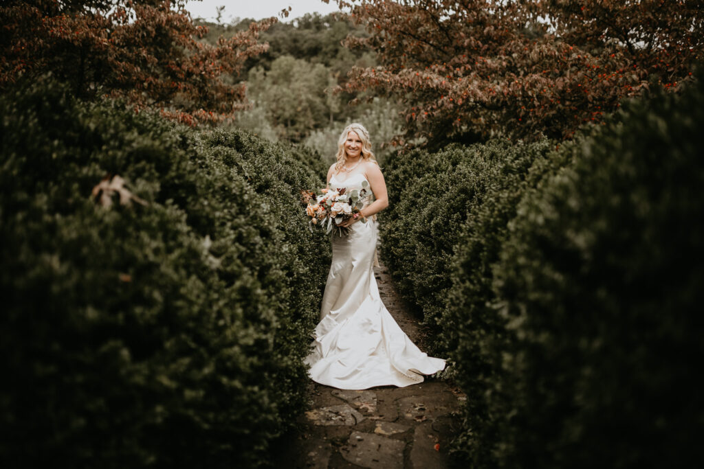 Photo by Pat Cori Photograpy of a bride posing for her wedding portraits surrounded by lush greenery. Wedding places in Virginia.