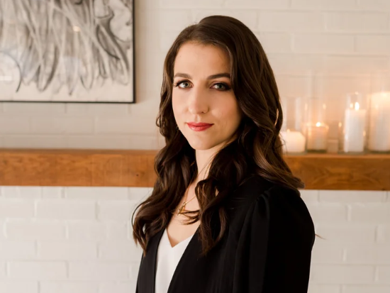 Photo of Julie at Vieira Events in DC She is posing in a black and white outfit in front of a shelf with candles and a painting.