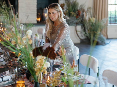 Photo of Laura from Grit and Grace Washington DC wedding planners dressing the table with florals and table ware getting ready for a wedding ceremony.