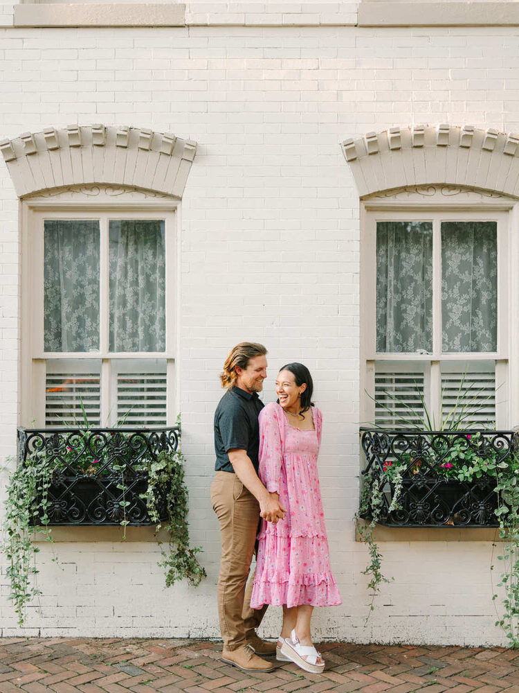 Photo By Pat Cori of a couple holding hands in front of a home surrounded ivy greenery window boxes.
