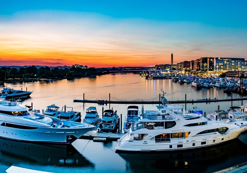 Photo of the Wharf with boats and yachts at sunset with the water and city in the background. Romantic date ideas for Washington DC.