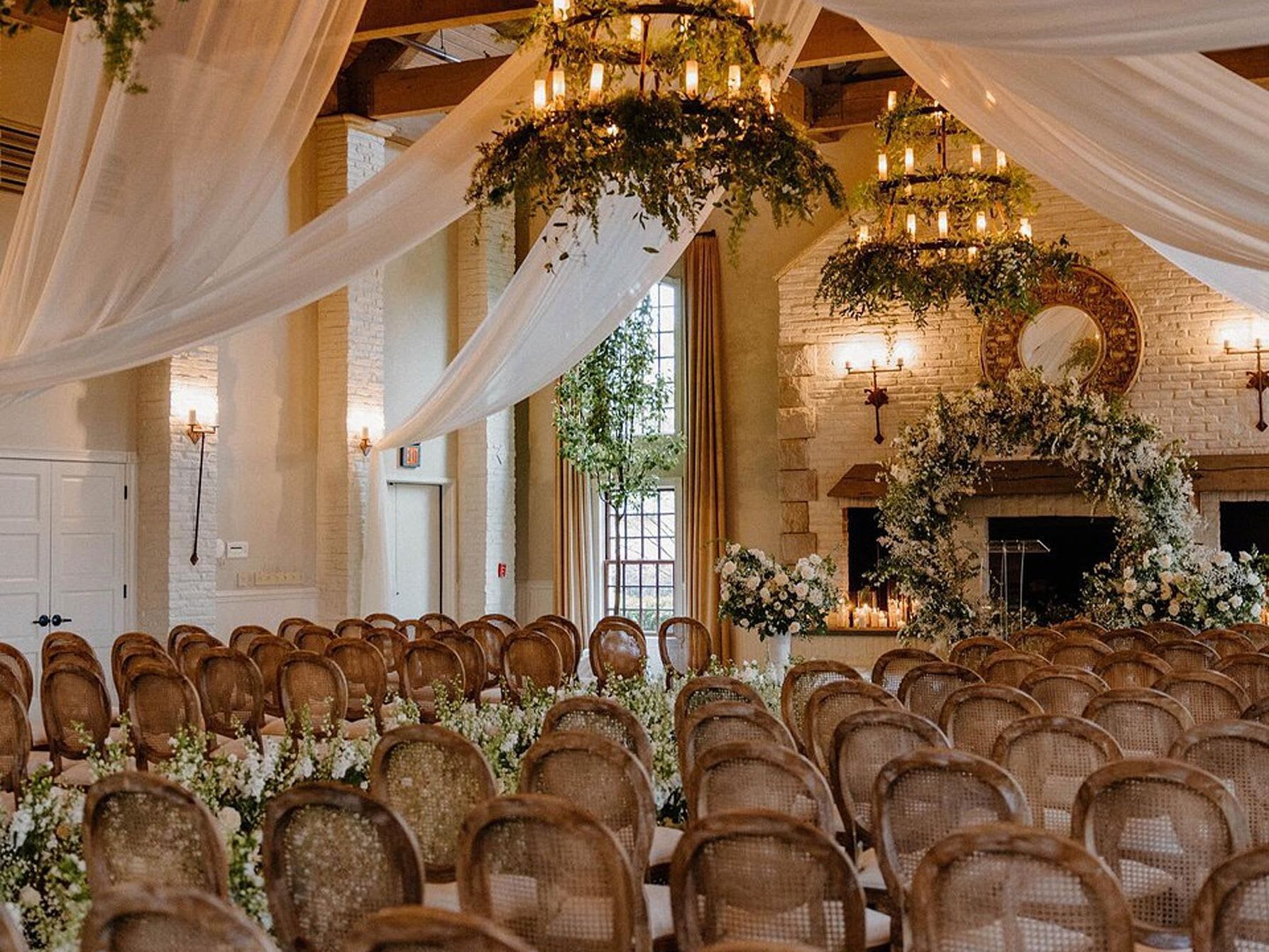 Photo of the Ceremony in Early Mountain with rows of chairs and large brick fireplace with sheer draping from ceiling. A wedding venue located in Virginia.