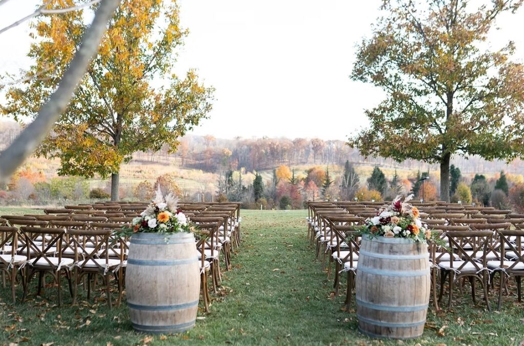 Ceremony are at The Market at Grelen surrounded by lush greenery and trees with the colors of fall. Rows of chairs for guest. A luxury venue in Virginia.
