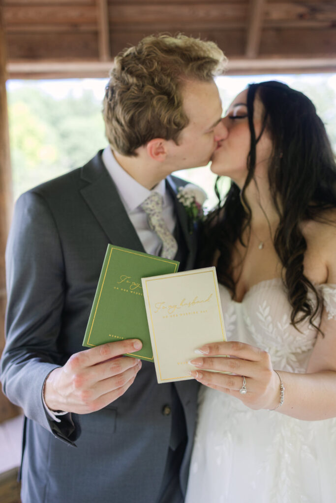 couple kissing holding their vow books in their hands