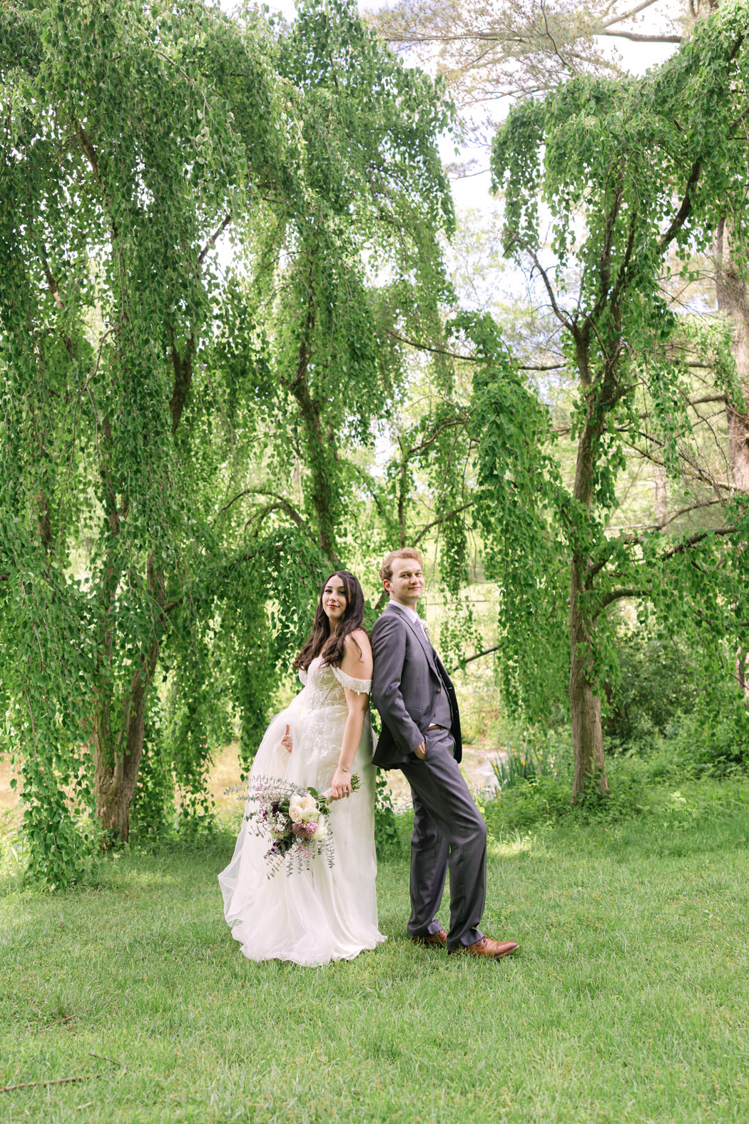 couple standing back to back surrounded by greenery