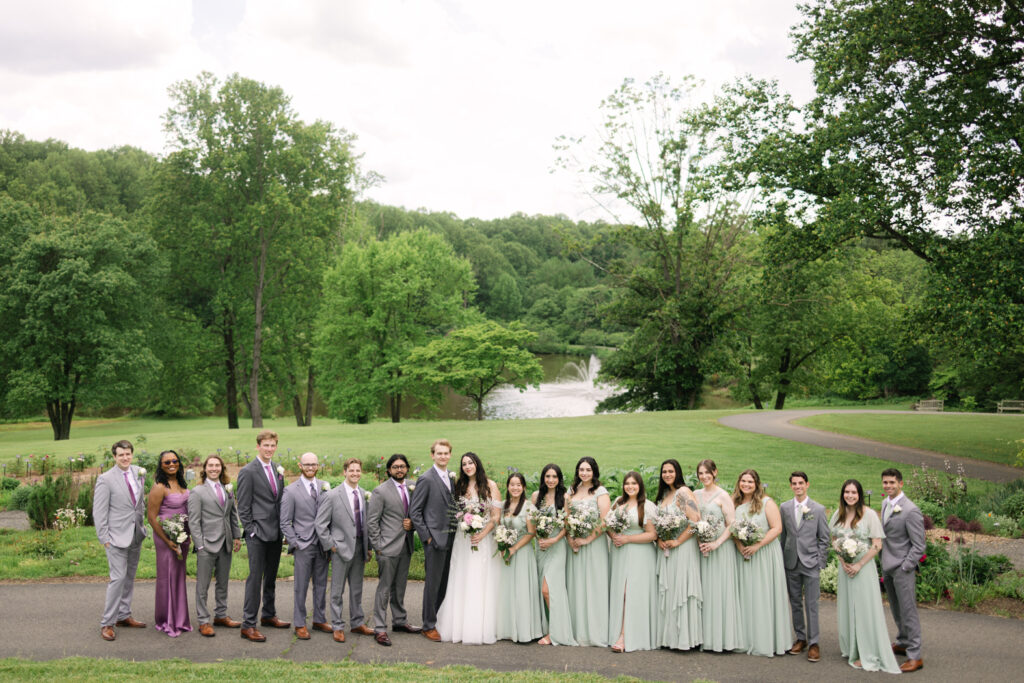 bridesmaids and groomsmen posing with the bride in their lavender and sage clothing
