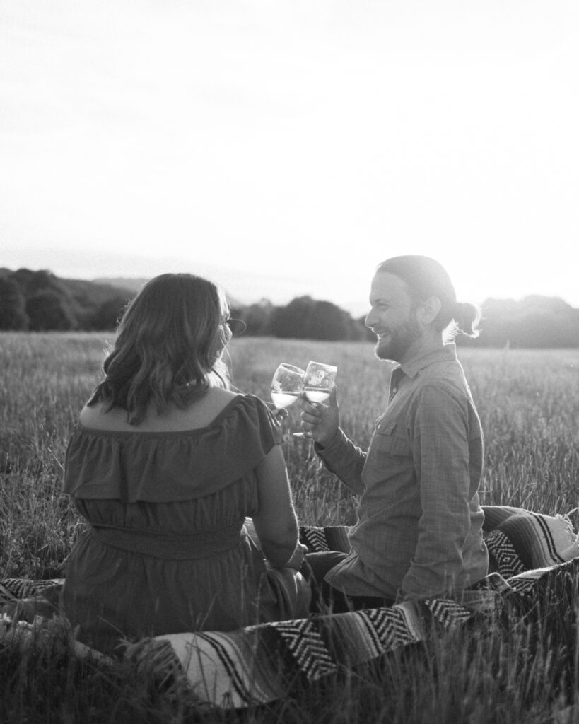 couple cheering at sunset at explore park for engagement pictures in black and white