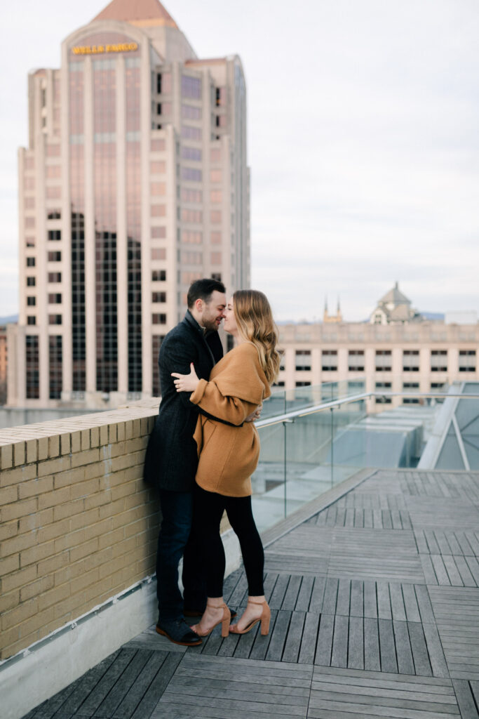 couple standing with wells fargo building in background engagement photos in roanoke
