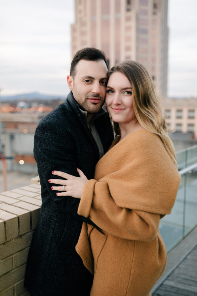 couple standing with wells fargo building in background engagement photos in roanoke