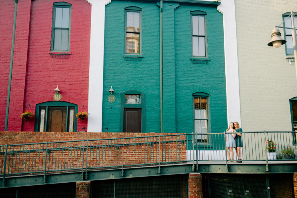 lesbian couple standing in front of colorful buildings