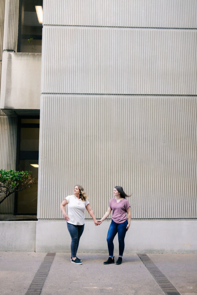 lesbian couple staing in front of a textured building