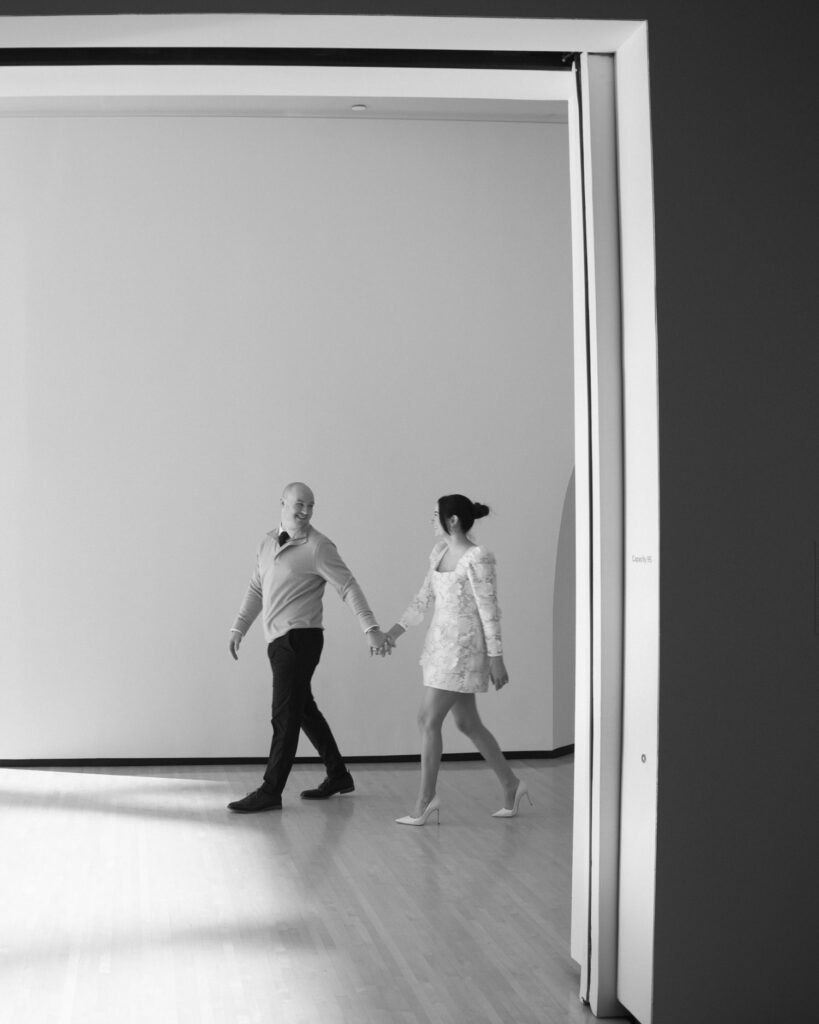 couple walking at the taubman museum for engagement photos in black and white