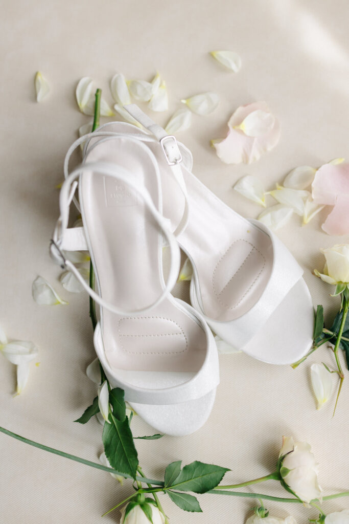 Bride’s white wedding heels styled with soft florals during getting ready at The Virginian Hotel in Lynchburg, VA.