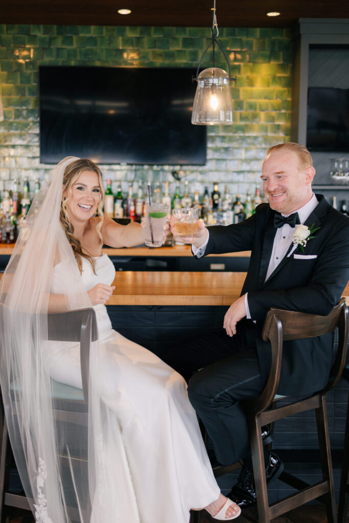 Bride and groom smiling and toasting at the bar during wedding portraits at The Skyline at The Virginian Hotel in Lynchburg, VA.
