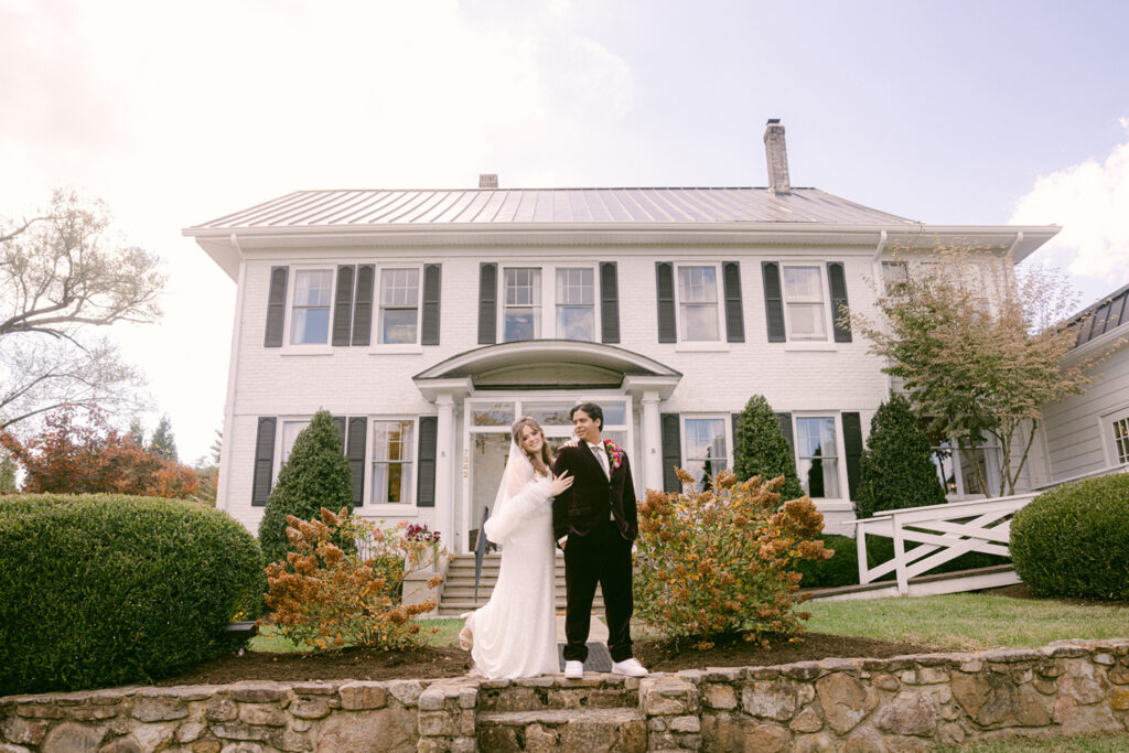 Bride and groom standing in front of a white historic estate home in Virginia, showcasing an intimate venue setting ideal for wedding venues for small weddings, captured by Pat Cori Photography