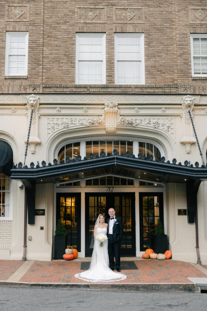 Bride and groom standing together at the entrance of The Virginian Hotel in Lynchburg during sunset portraits outside the historic venue