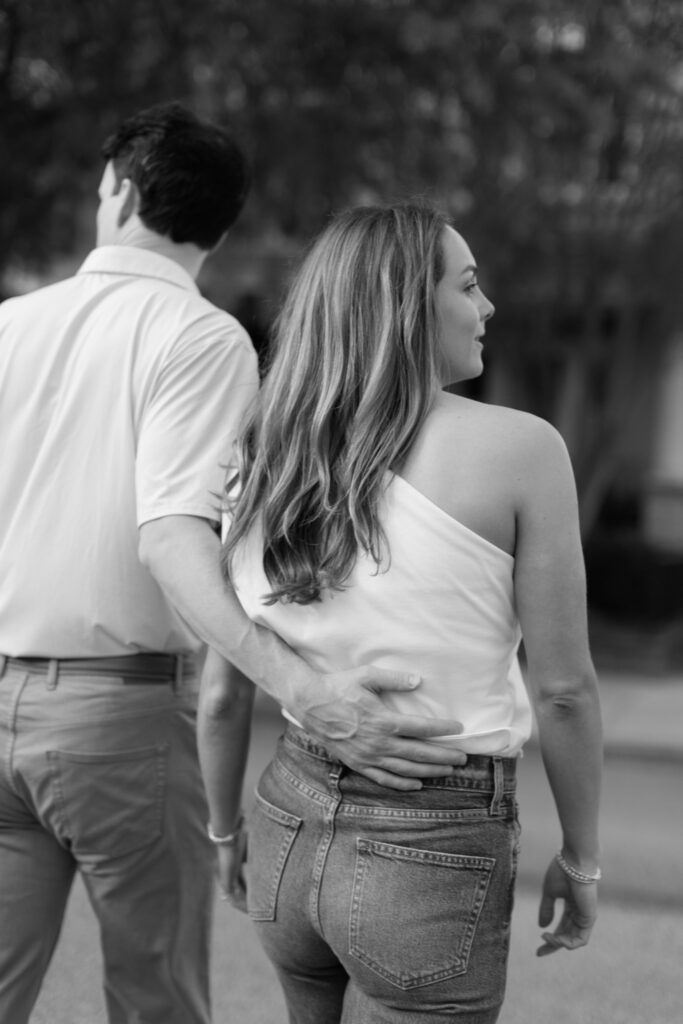 Black and white candid photo of couple walking arm in arm during Downtown Richmond engagement photos