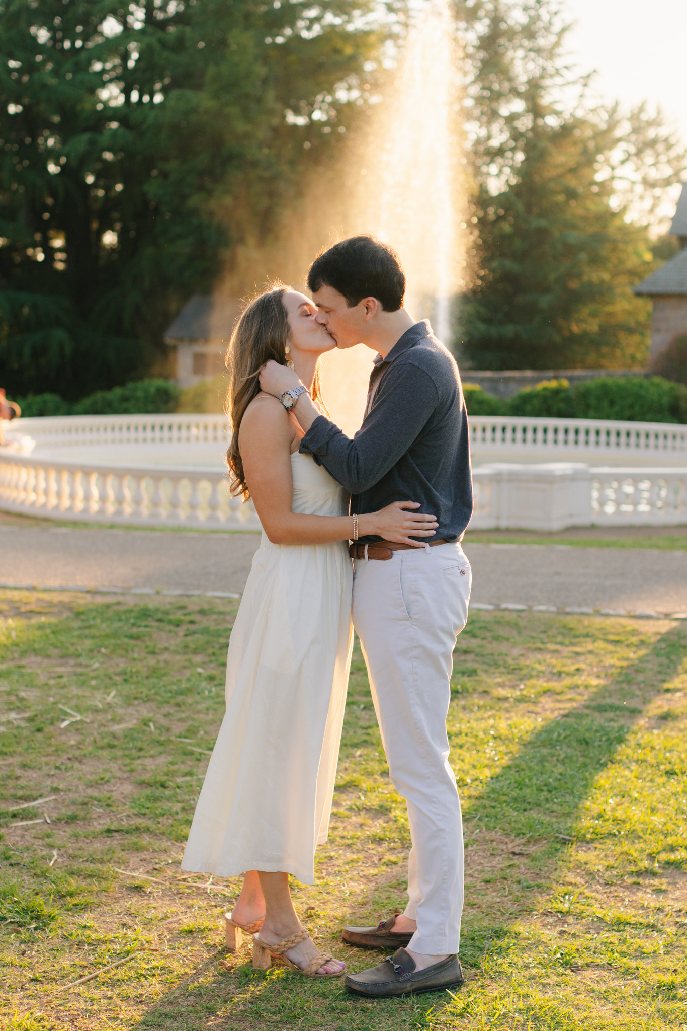 Couple kissing in front of glowing fountain during golden hour Maymont engagement photos in Richmond Virginia