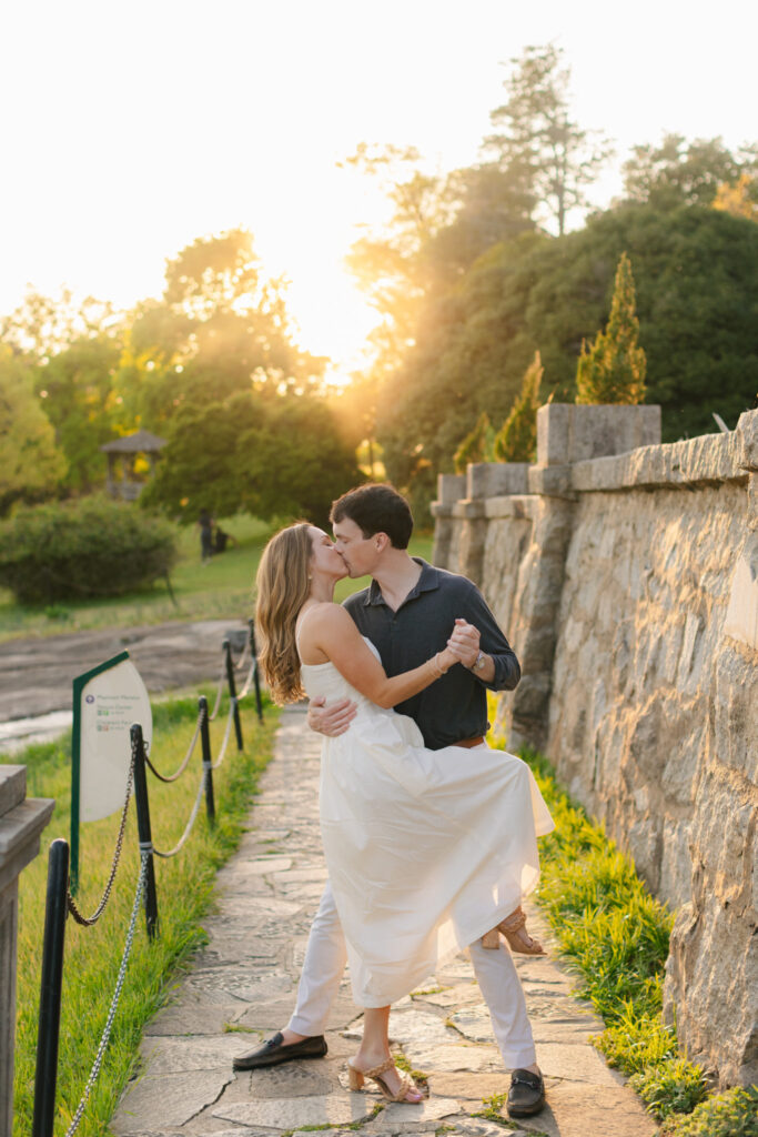 Couple kissing while dancing on stone pathway at sunset during Maymont engagement photos in Richmond Virginia