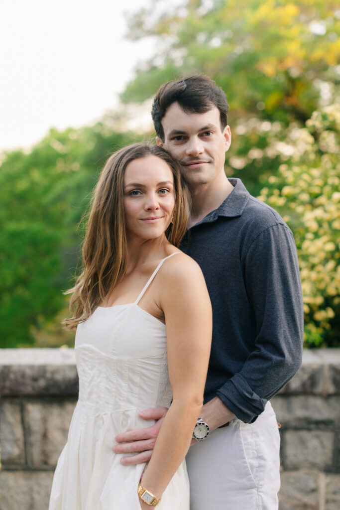 Image 30 alt text: “Close portrait of engaged couple embracing at Maymont Park in Richmond Virginia, dressed in elegant neutral outfits with soft greenery in the background