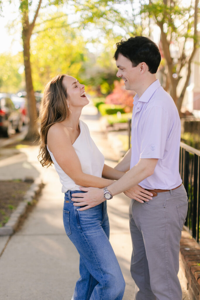 Laughing couple holding each other during spring engagement photos in Downtown Richmond.
