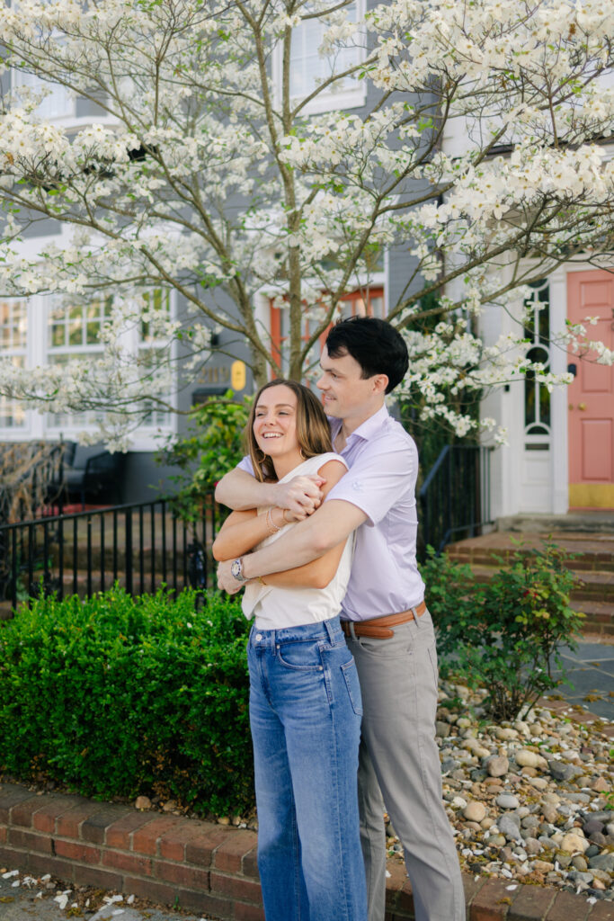 Couple embracing under white flowering tree during spring Downtown Richmond engagement photos