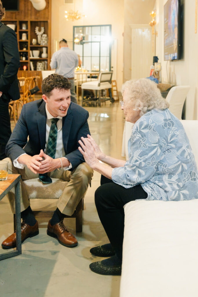 Wedding guest laughing while talking with an older family member during the rehearsal dinner at The Georges in Lexington, Virginia