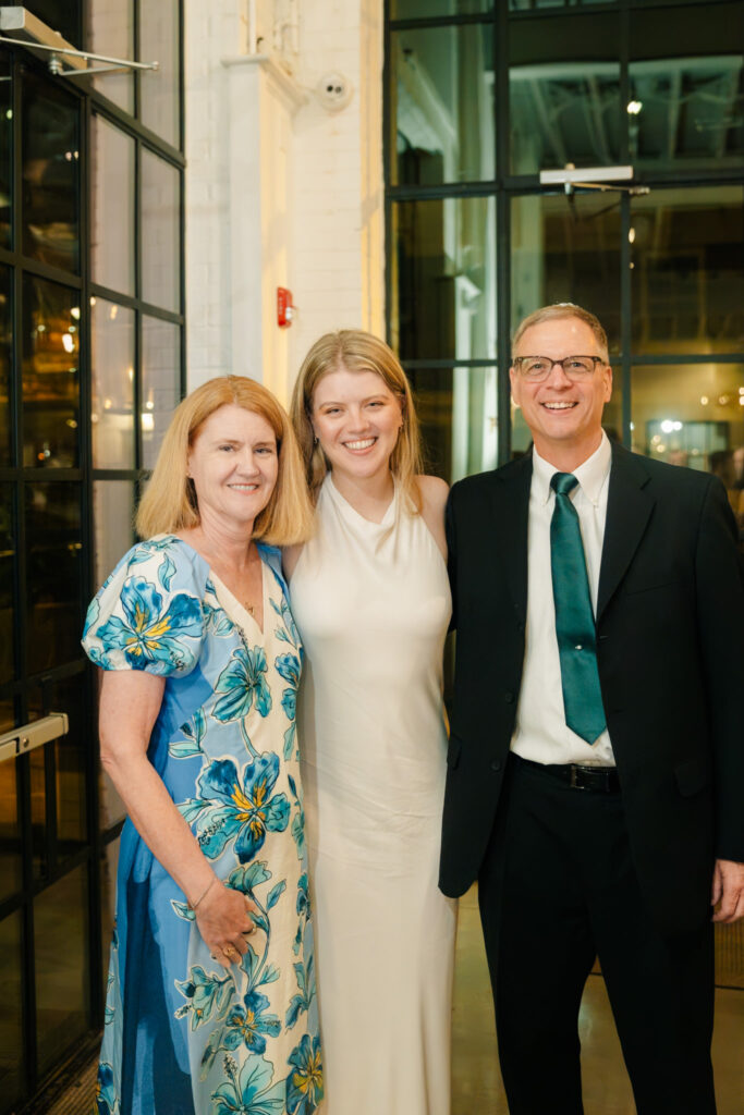 Bride in a white rehearsal dinner dress posing with family during her rehearsal dinner at The Georges in Lexington, Virginia