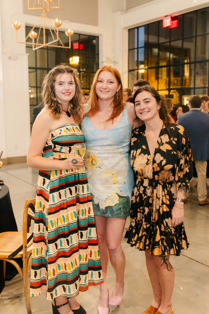 Four wedding guests in colorful dresses posing together during the rehearsal dinner at The Georges in Lexington, Virginia
