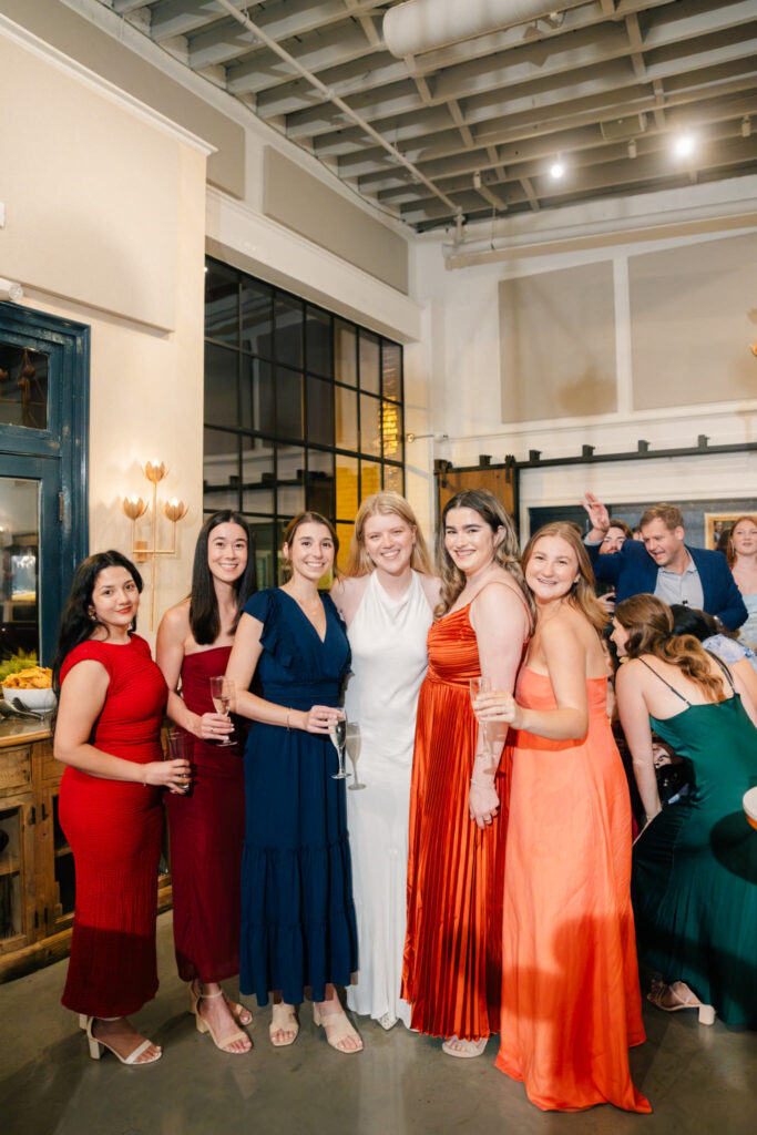 Bride in a white rehearsal dinner dress surrounded by friends in colorful formal dresses at The Georges in Lexington, Virginia