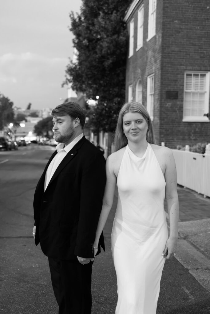 Black-and-white portrait of a bride and groom holding hands on a historic street in downtown Lexington, Virginia