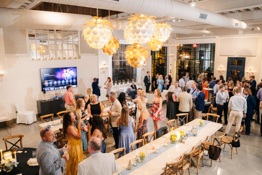 Rehearsal dinner ideas at The Georges in Lexington, Virginia, with guests mingling around long dinner tables during an indoor wedding weekend celebration