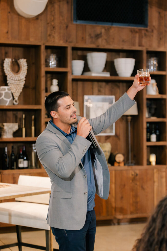 Guest raising his glass during a toast while speaking into a microphone