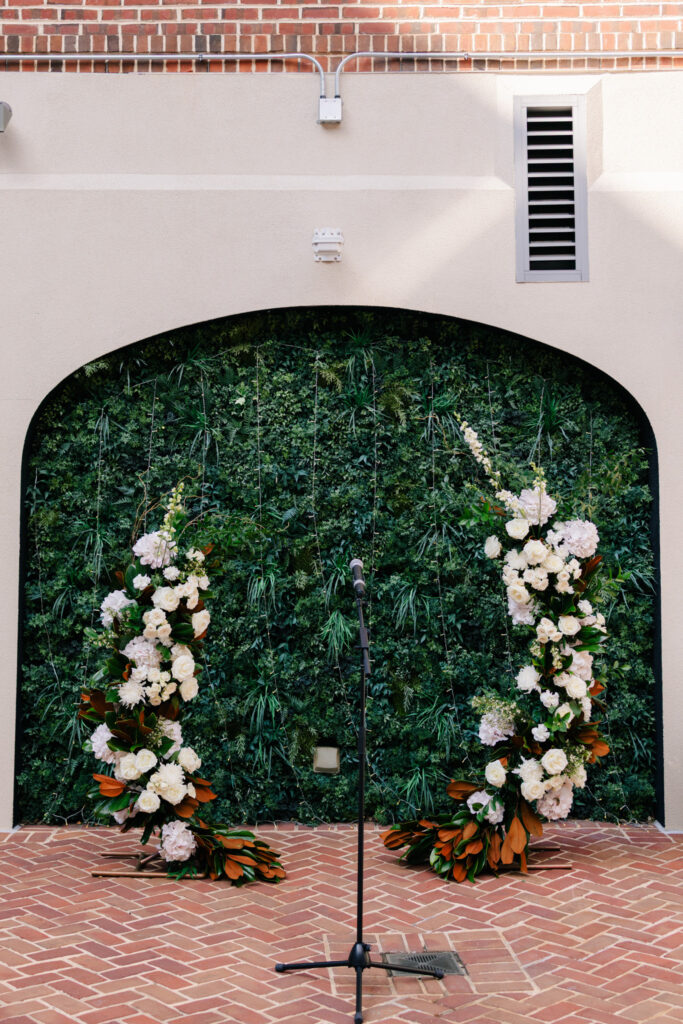 White floral ceremony installation with lush greenery and magnolia leaves in The Alexandrian Hotel courtyard in Alexandria, Virginia