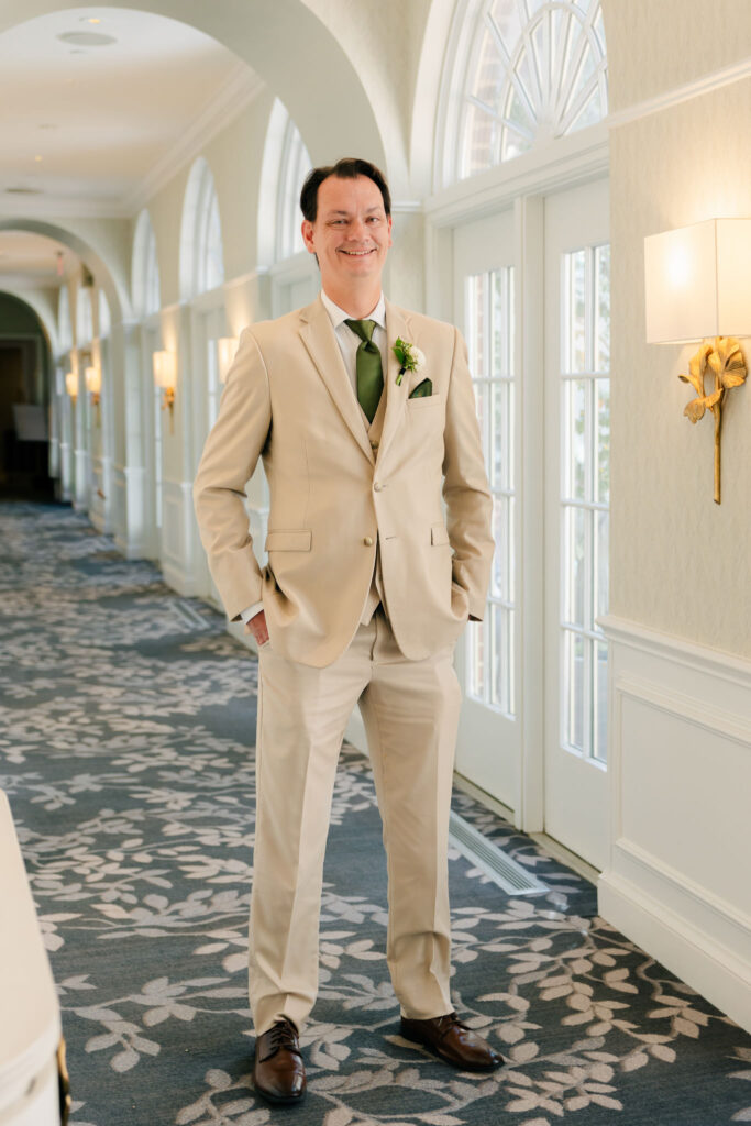 Groom in a tan suit waiting for his first look inside The Alexandrian Hotel in Alexandria, Virginia
