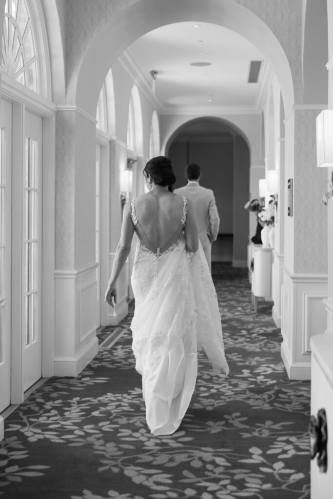 Bride walking toward the groom for their first look in an elegant arched hallway at The Alexandrian Hotel