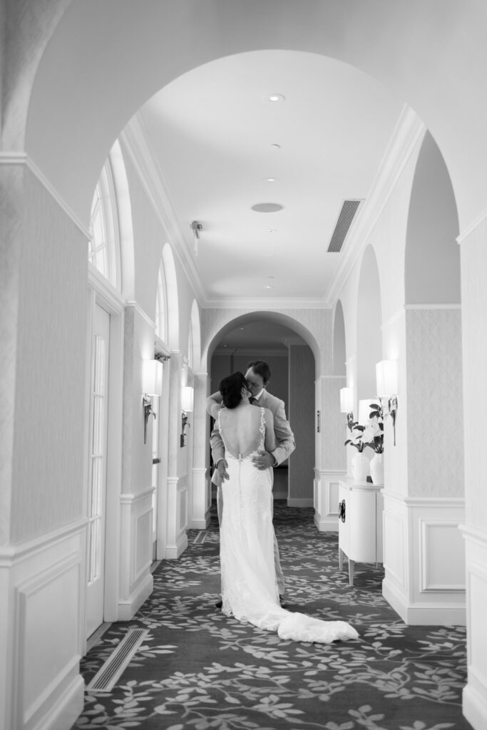 Bride and groom sharing a quiet kiss during their first look in the elegant hallway of The Alexandrian Hotel
