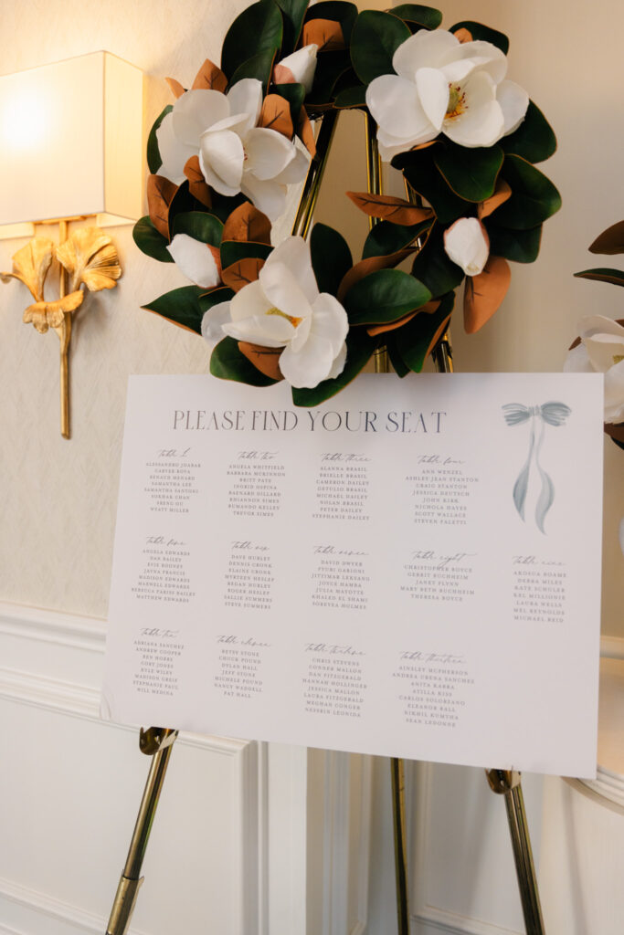 Wedding seating chart decorated with magnolia leaves and white flowers at The Alexandrian Hotel in Alexandria, Virginia.