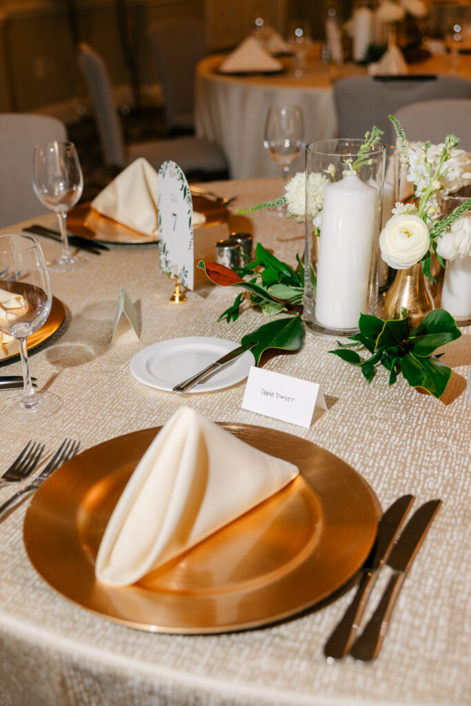 Elegant wedding reception table setting with gold chargers, white florals, greenery and candlelight at The Alexandrian Hotel in Alexandria, Virginia