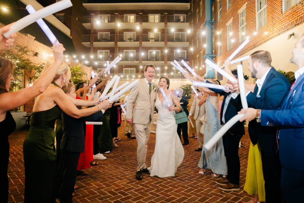 Bride and groom laughing during their glow stick grand exit in the courtyard at The Alexandrian Hotel in Old Town Alexandria, Virginia.